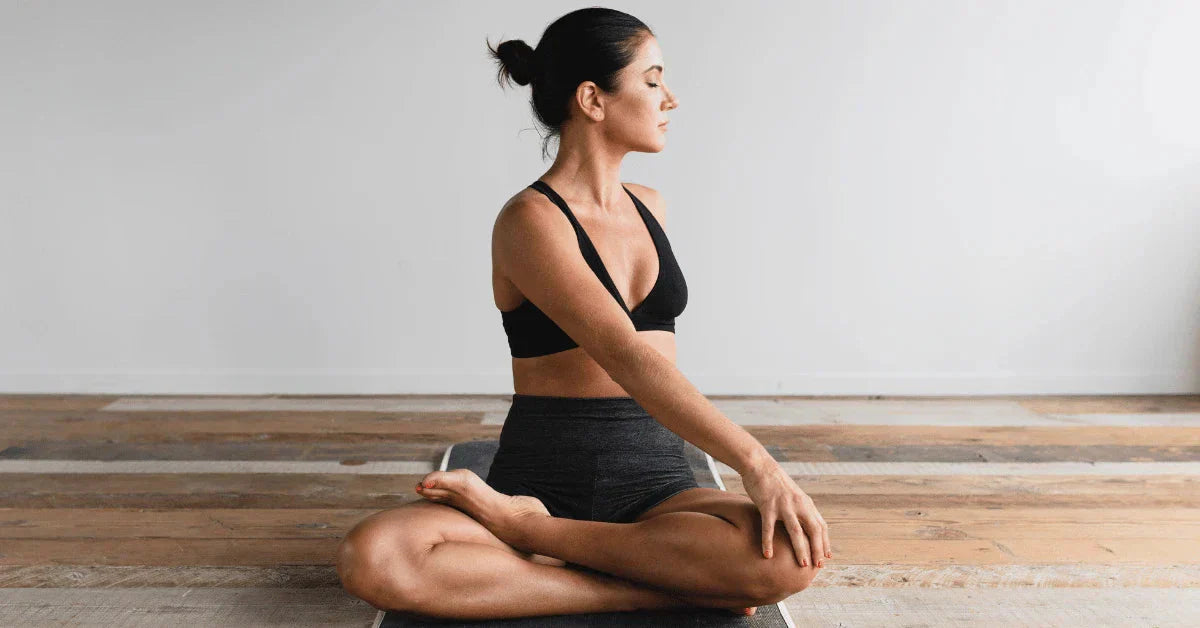 Woman sitting on the floor with legs crossed and twisting her upper body  to stretch her spine