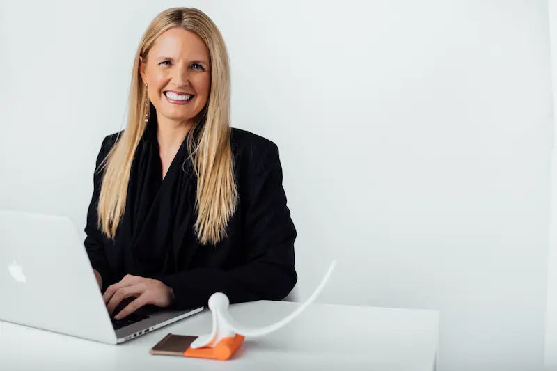 Woman sitting at a desk with a laptop and phone